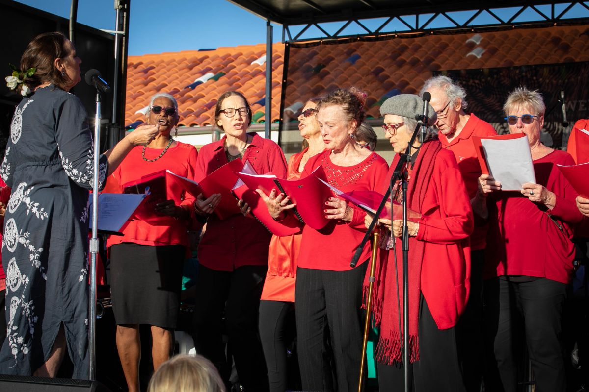 A very happy group of seniors standing on stage together singing