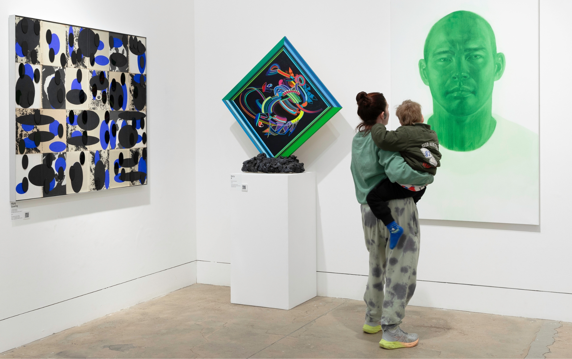 Image of a woman holder a child and viewing the Waverley Art Prize exhibition