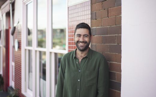Jonathan Seidler is a man with short dark cropped hair and beard. He stands, smiling to the camera in a khaki button up shirt.