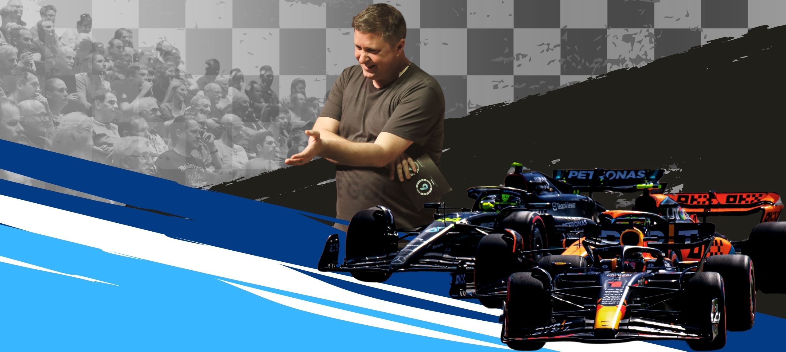 David Croft talking to an audience with two formula 1 cars on the side