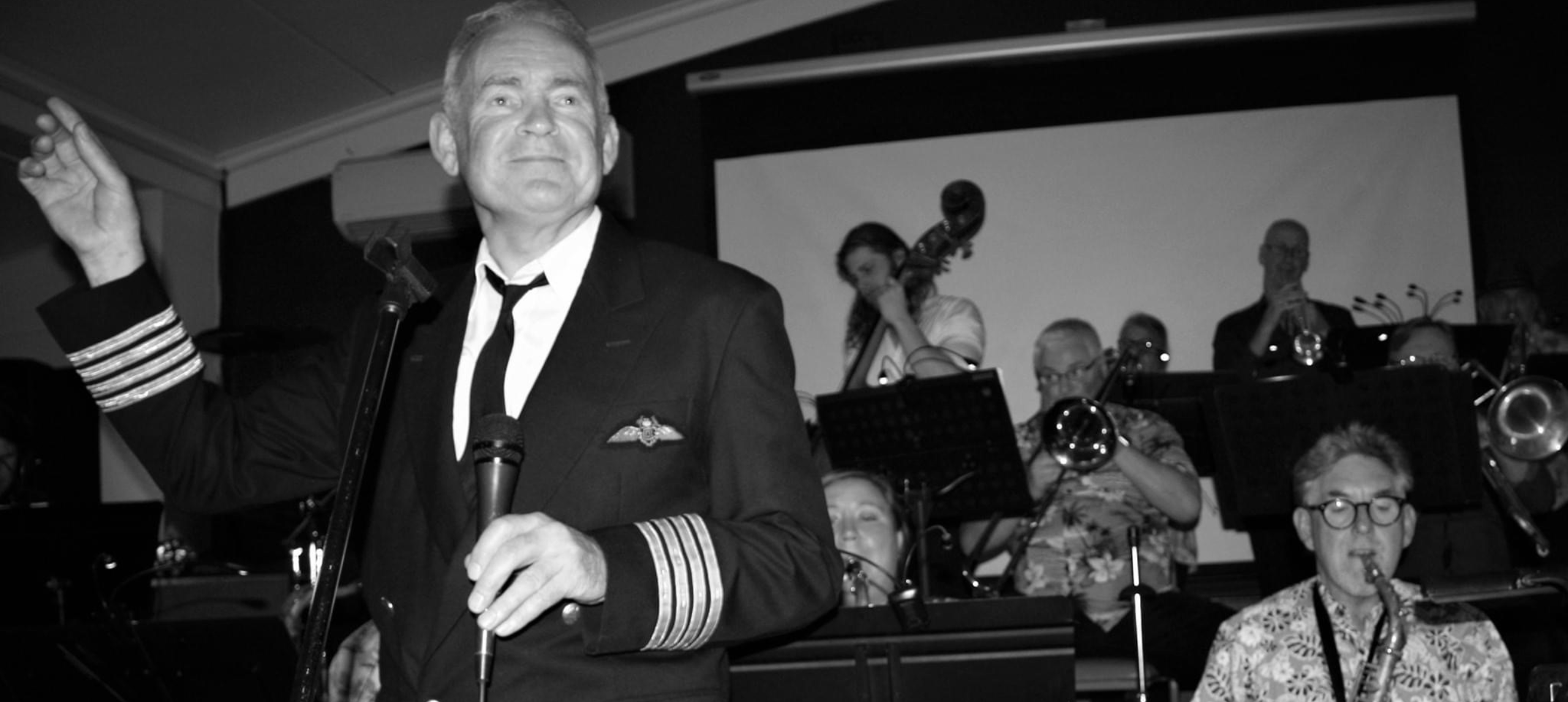 Male singer out front of a big band in black and white