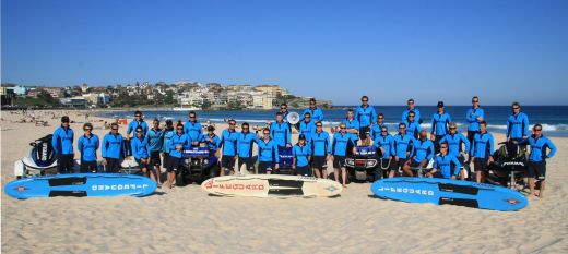 Bondi Lifeguards in uniform, posing on Bondi Beach with the ocean in the background