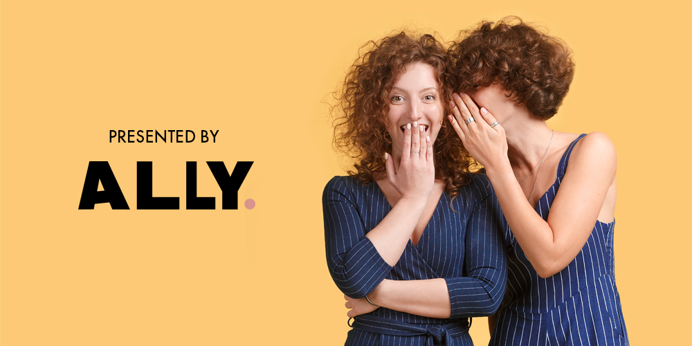 Two women with curly auburn hair whisipering to each other