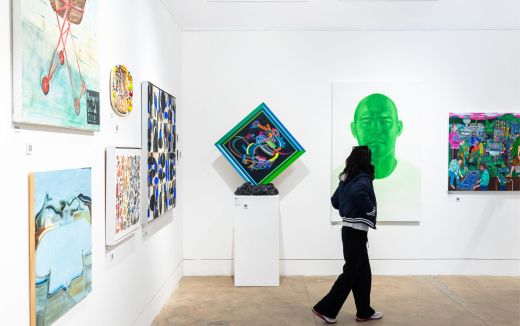 A person walks through a gallery with contemporary art on the walls and plinths.