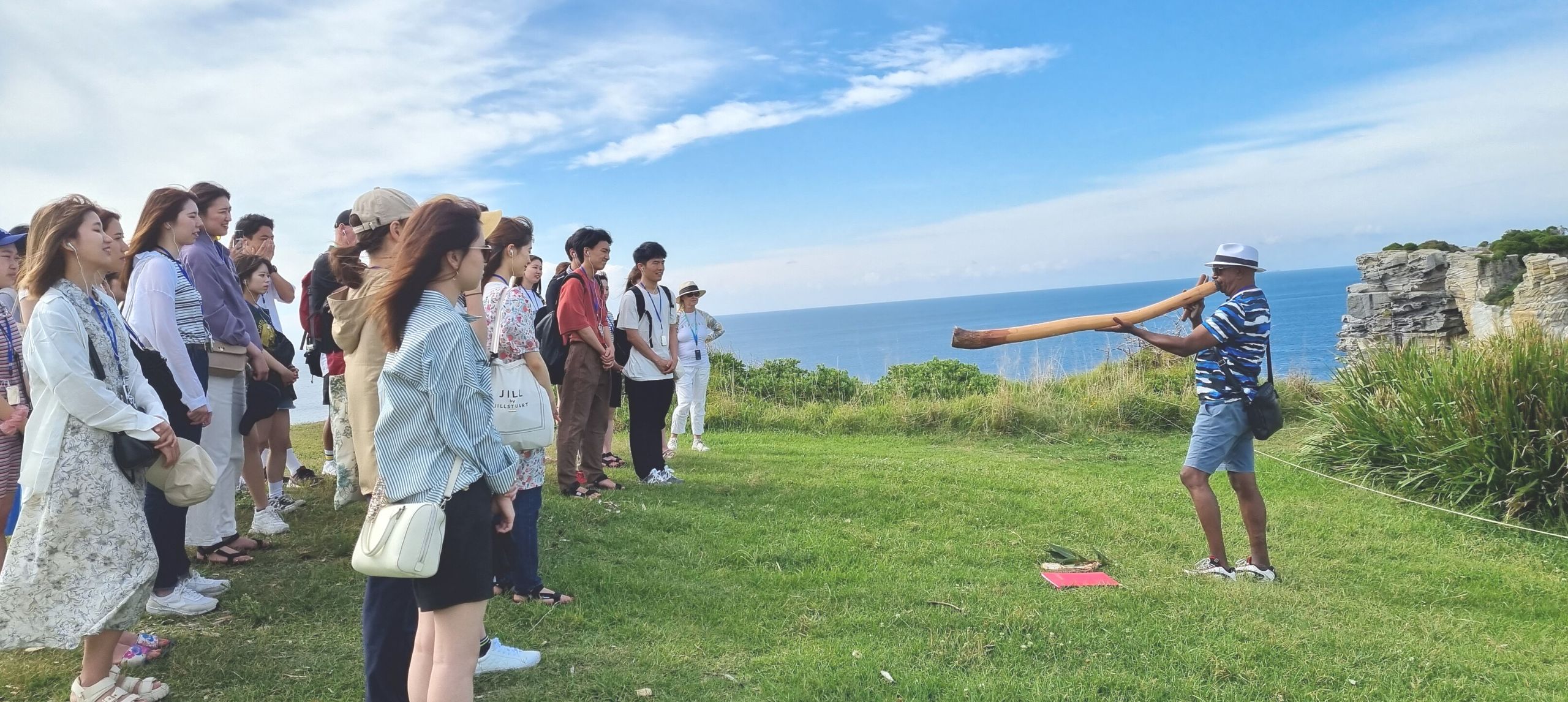 Walangari playing didgeridoo for a group of studentson north Bondi's headland