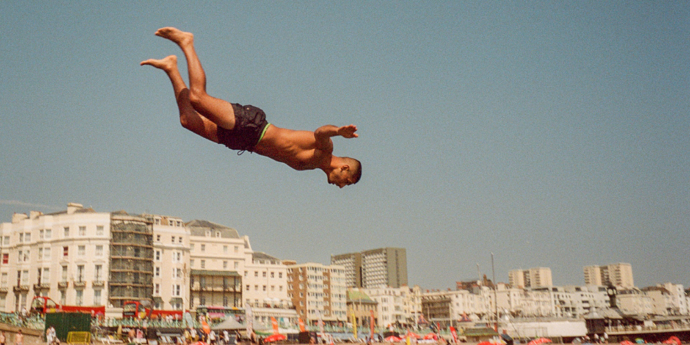 Picture of a man diving with city buildings in the background