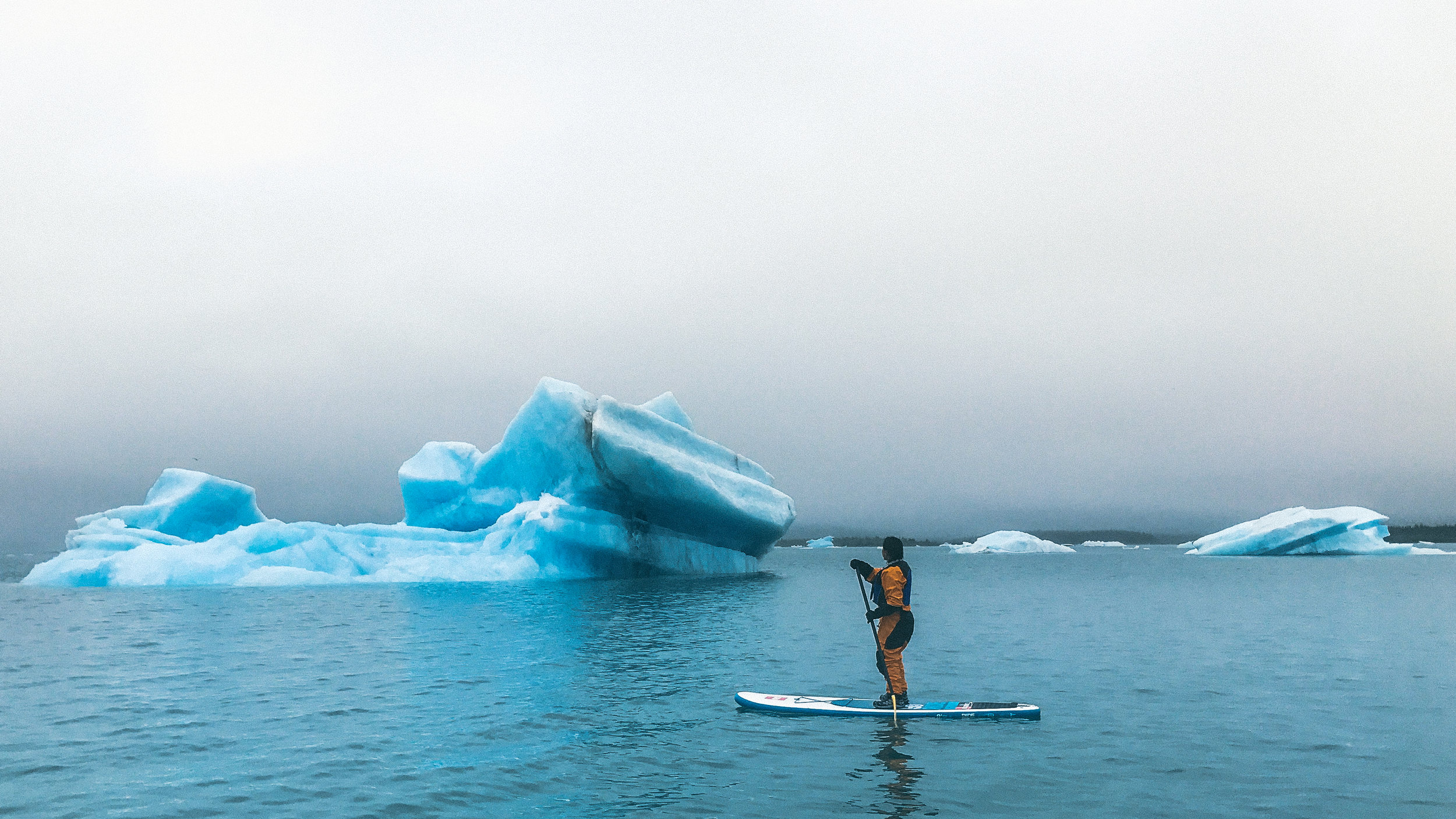 Solo paddle boarder with icebergs