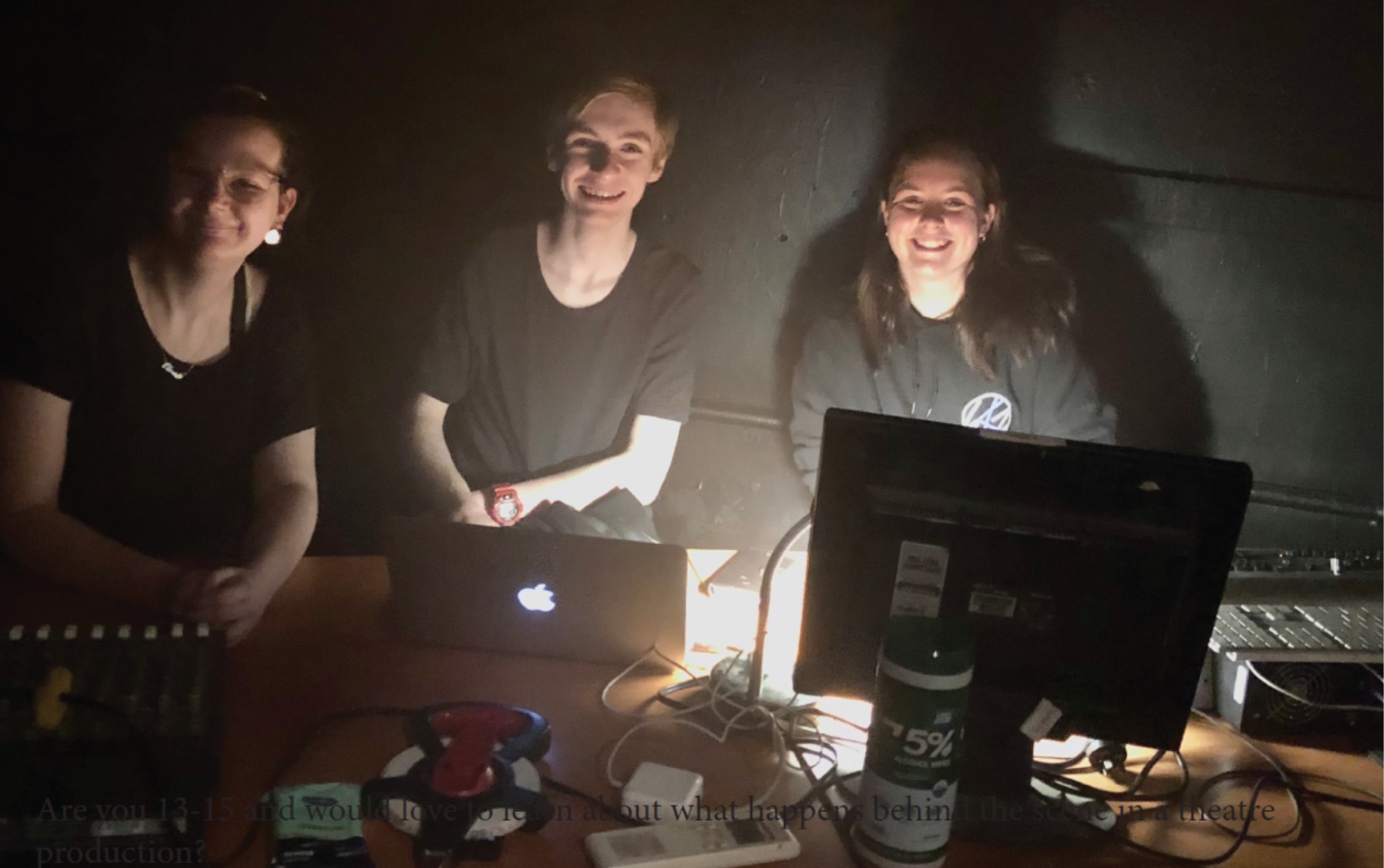 Three students sitting at a desk with computers and cords around them