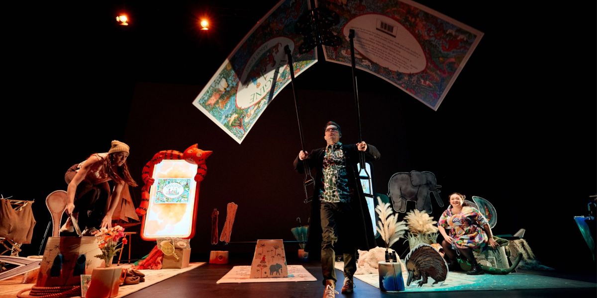 Actors on stage with a giant book being held up in the air