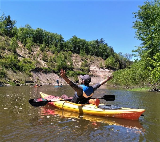 Male rower solo surrounded by trees and blue sky