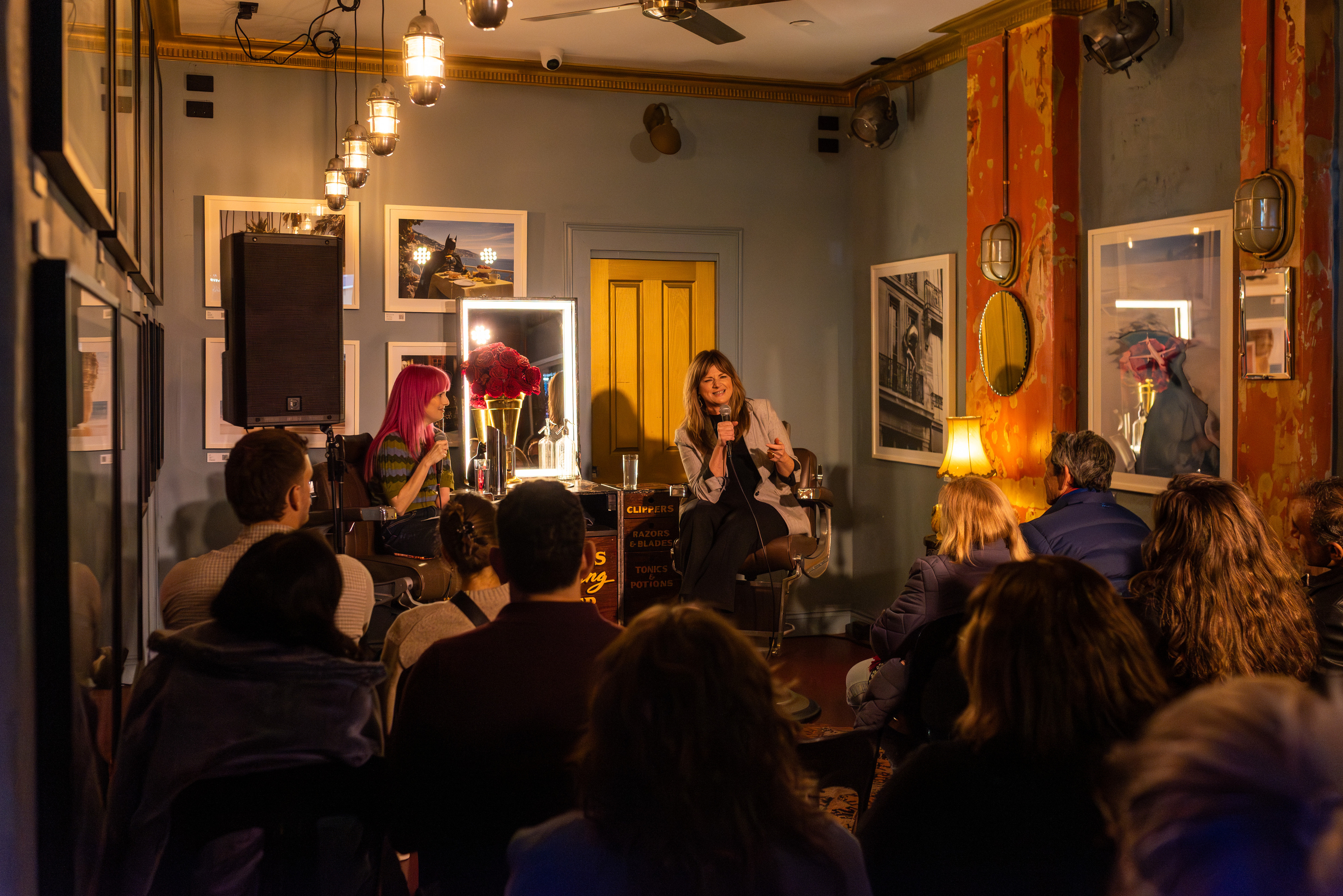 A pink hair woman interviews another woman in a barbershop