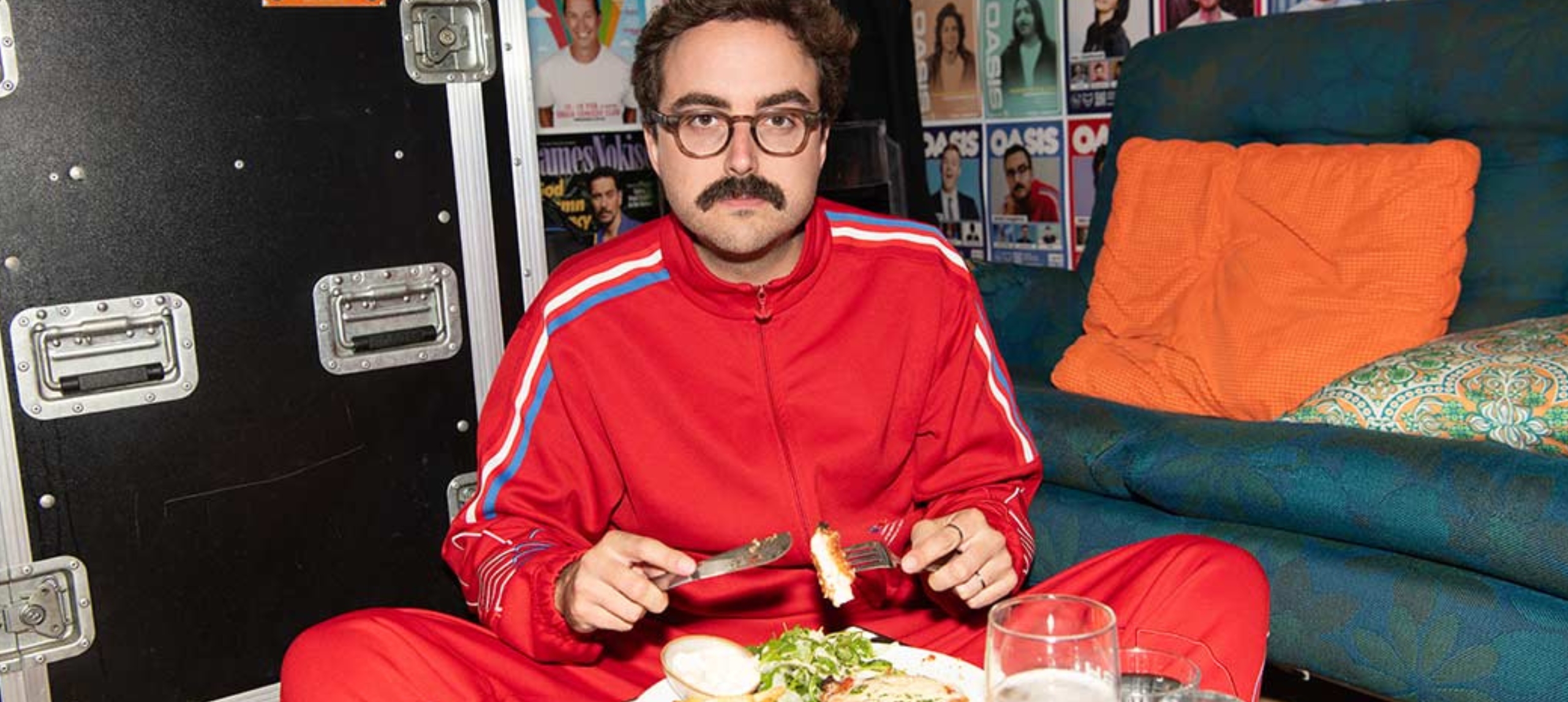 Daniel seated, wearing red tracksuit eating