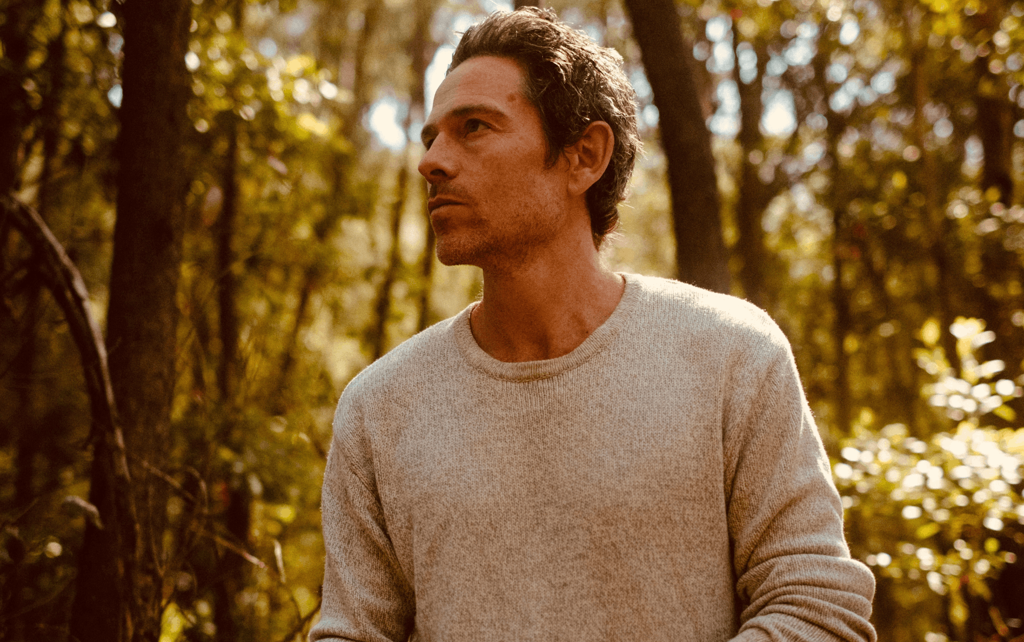 Man with a jumper in a leafy forrest environment