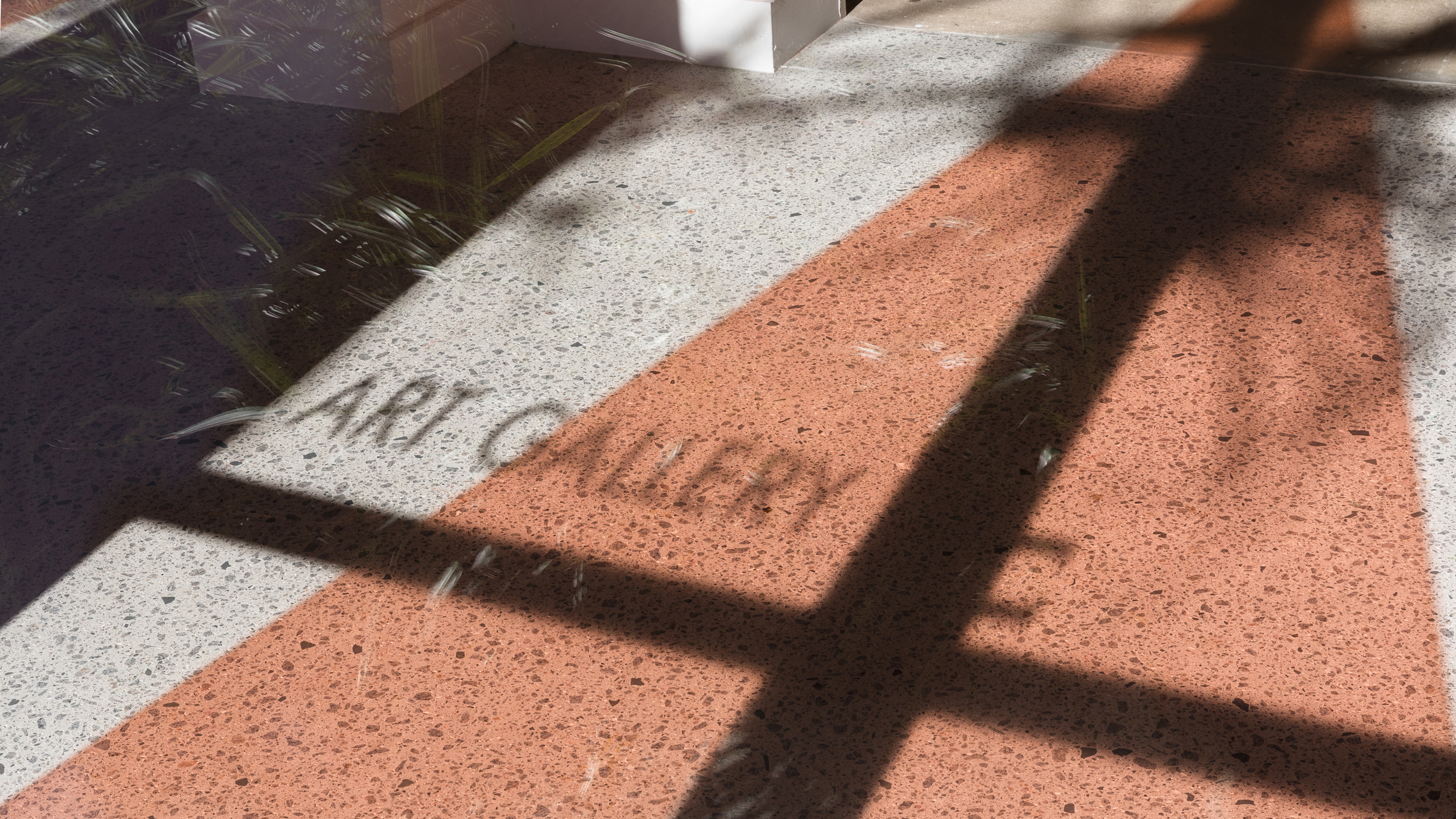 A photograph of a gallery window with reflected letters on the ground saying 'art gallery'.