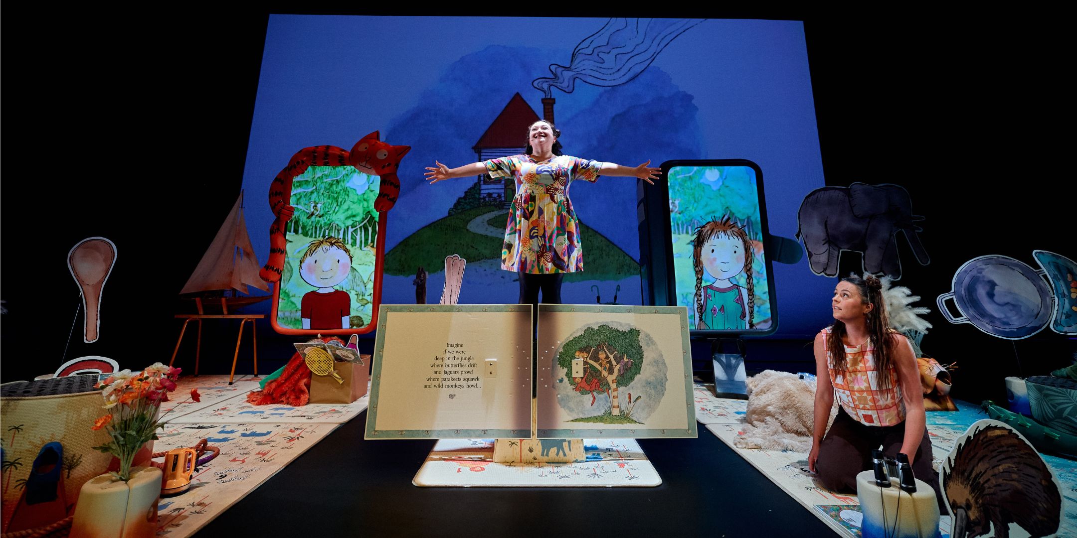 Girl on stage with arms outstretched in front on a big Imagine Live Screen