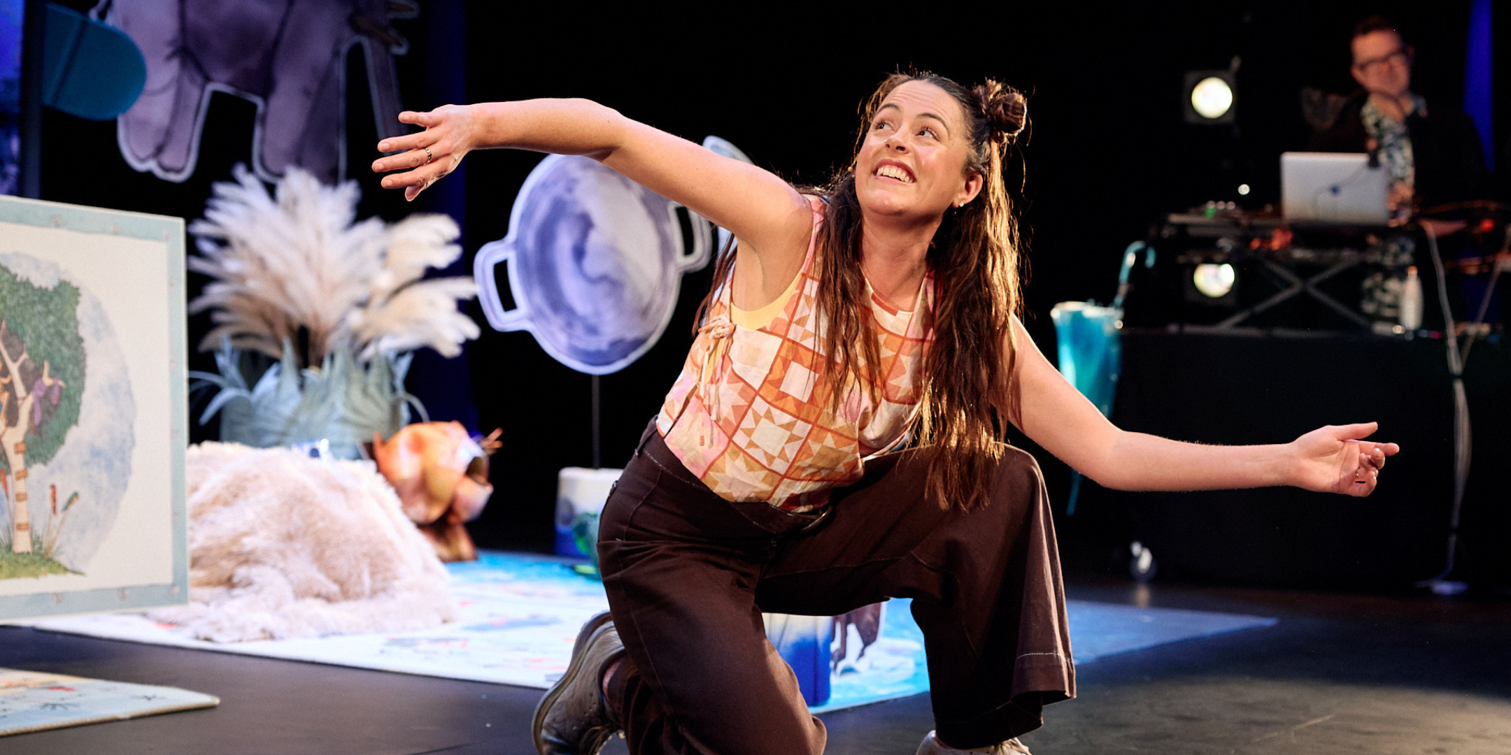 Actor with pig tails bending one knee while she's singing and dancing