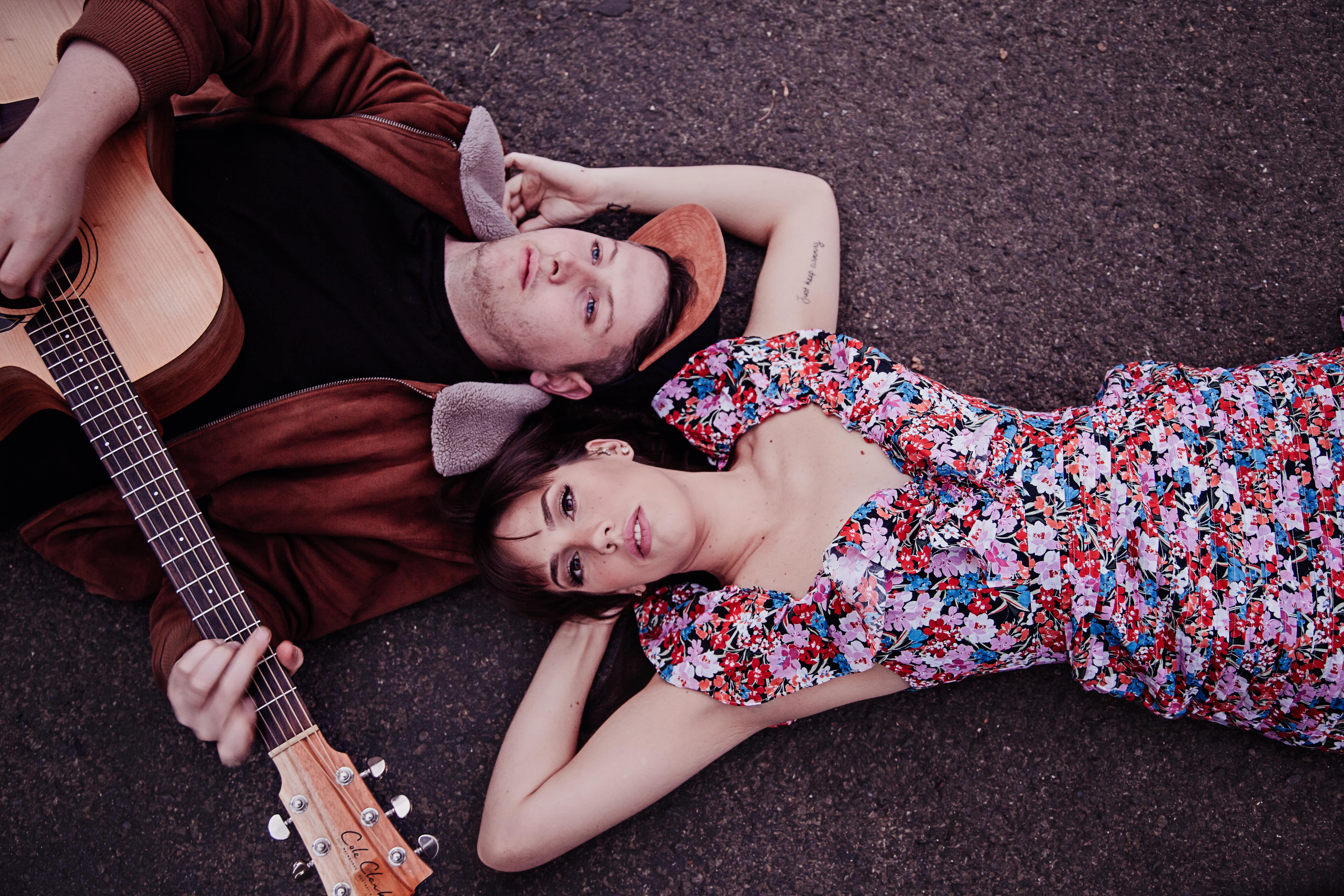 A male and Female musician lying on the ground with heads touching