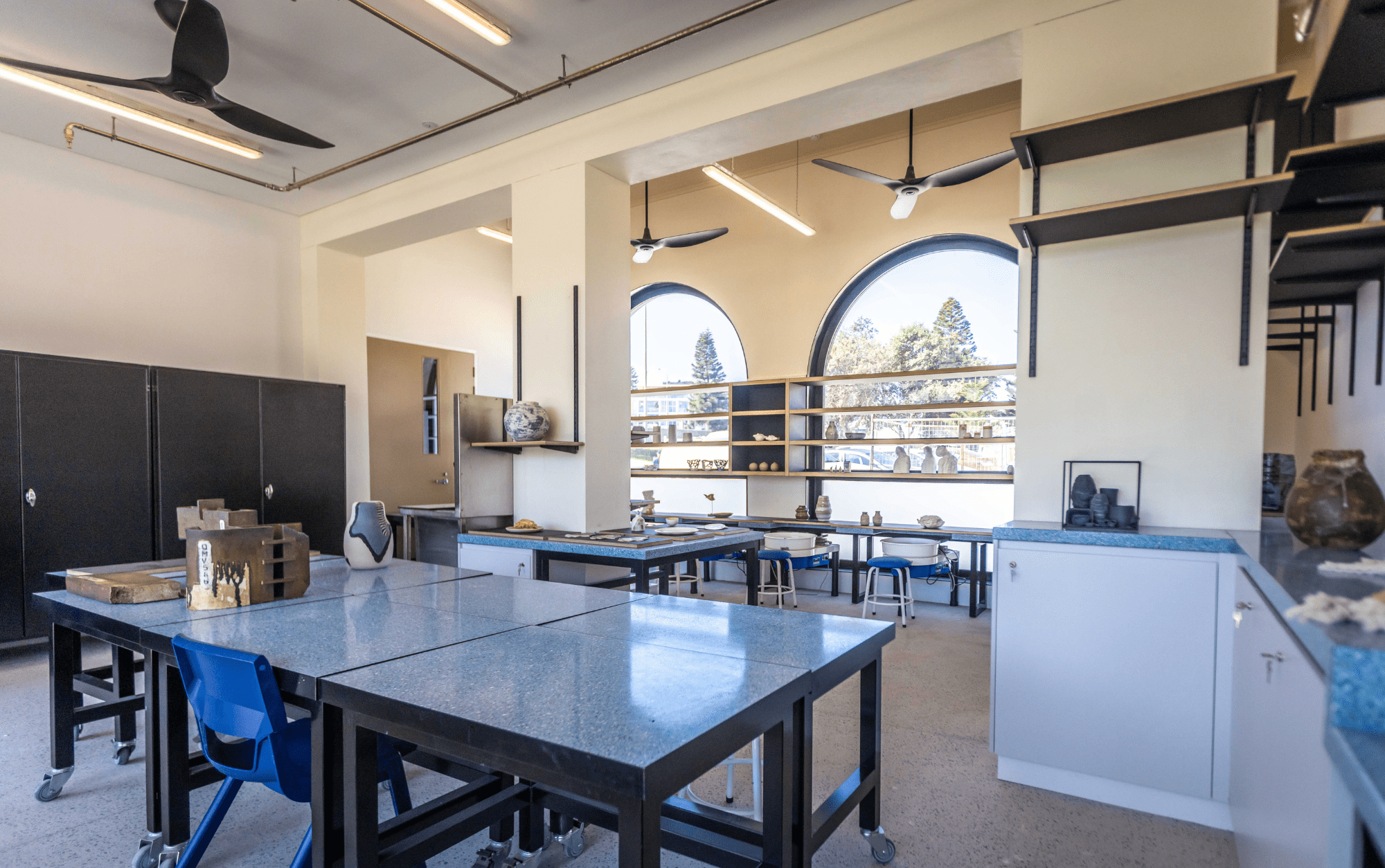 Pottery studio tables and pottery wheels with shelves displaying clay artworks