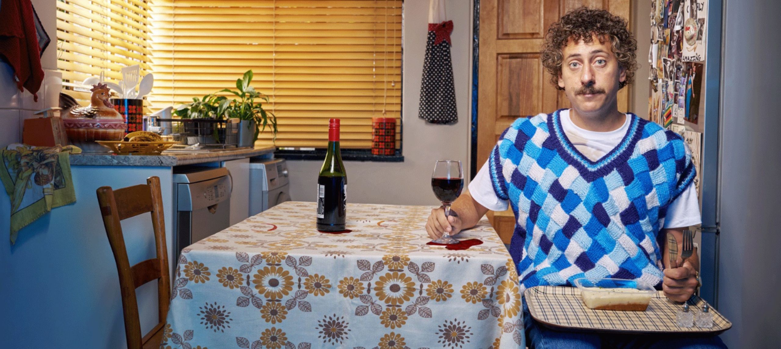 Schalk Bezuidenhout sitting at kitchen table - blue checkered vest