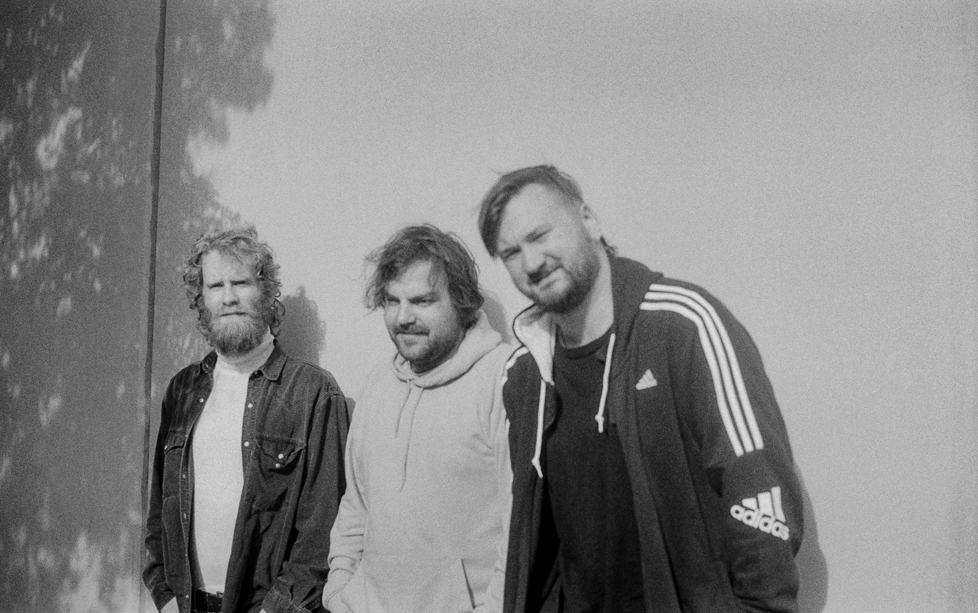Black and white image of three jazz musicians standing in front of a wall