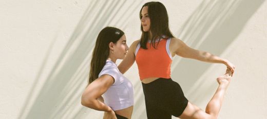 Orange background two pilates teachers doing pilates poses 