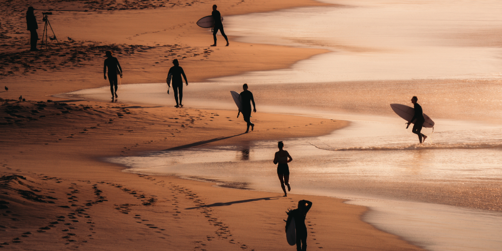 Surfers moving along a sunset beach