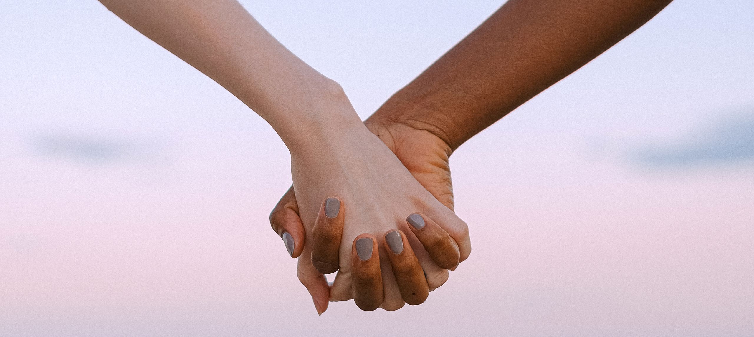 Two hands holding with sunset pink and blue