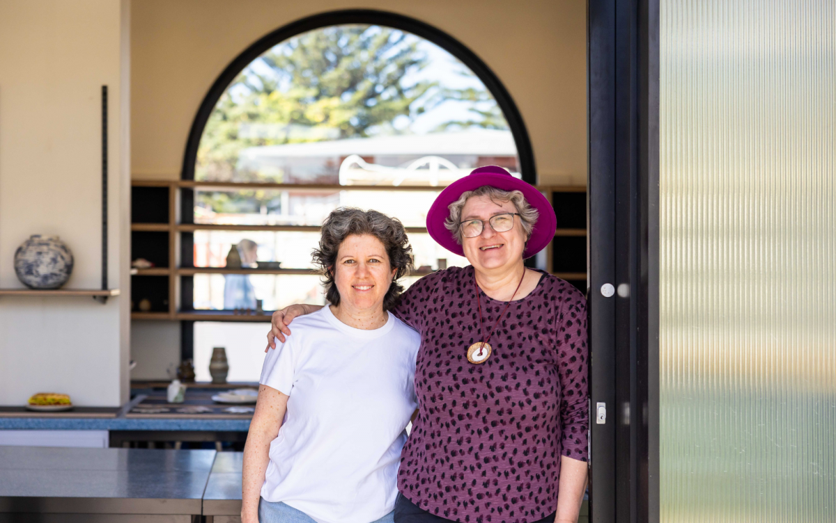 Two ladies who run the bondi pav pottery studio smiling in front of the light filled arches of the studio