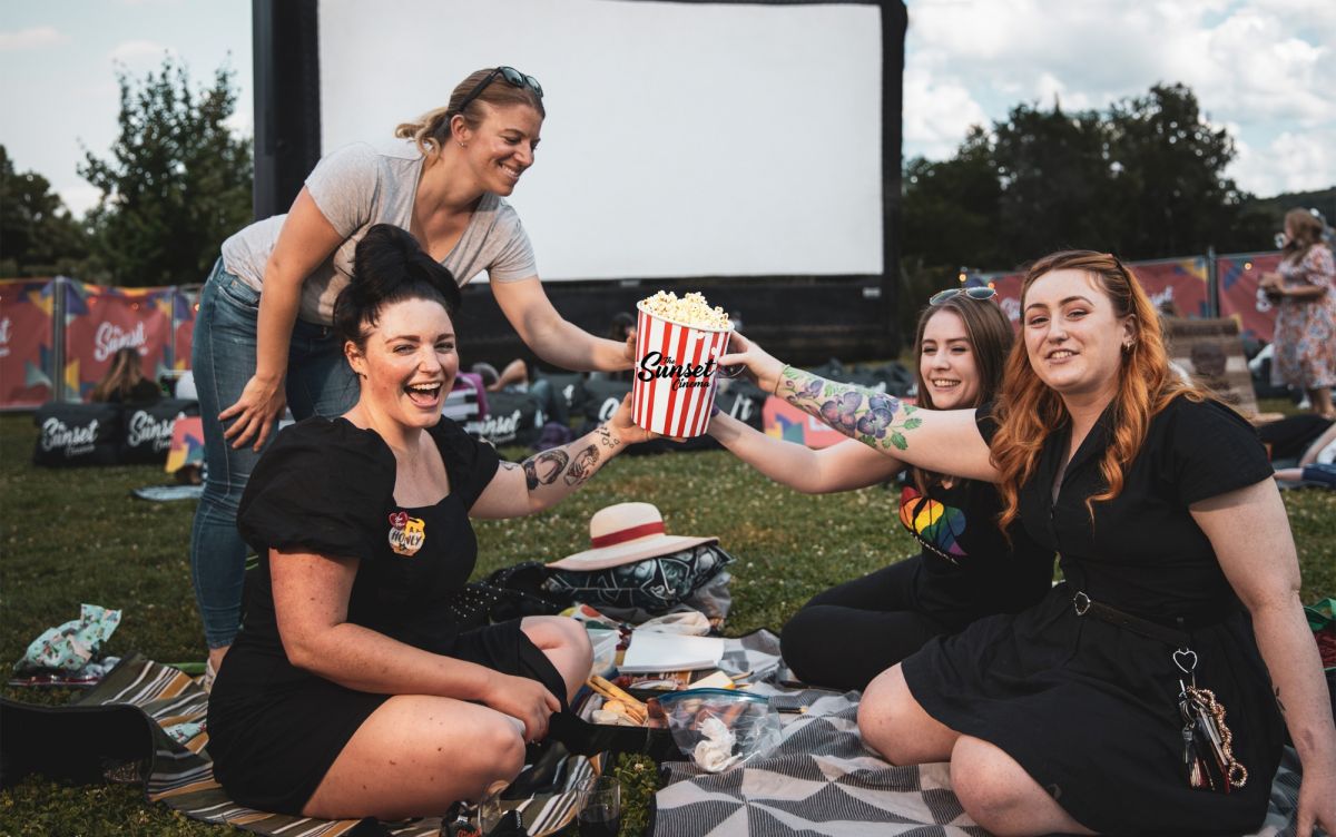 Group of girlfriends sitting on grass with popcorn