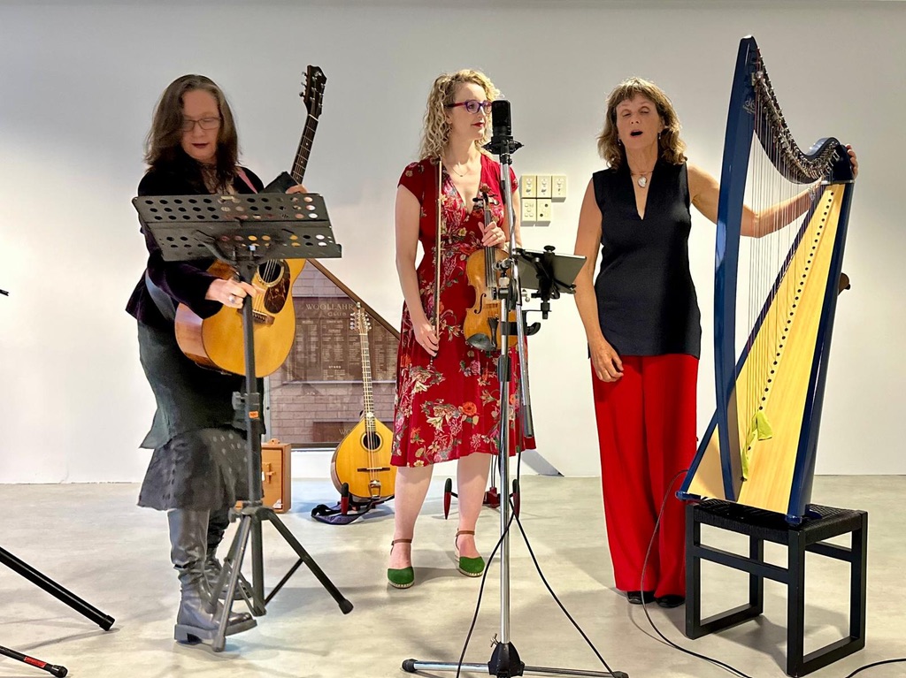 Three women in a white room with instruments performing