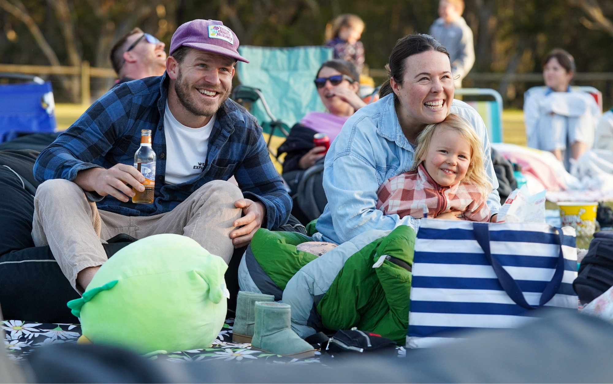 Young couple sitting on bean bags on grass with toddler