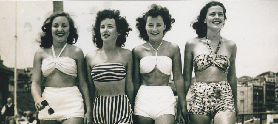 Four women in 1950s swimwear walking on Bondi Promenade.