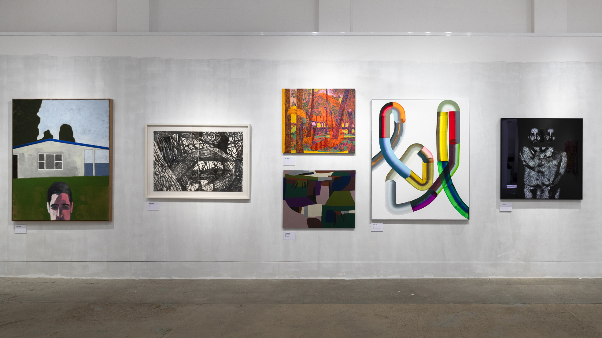 A photograph of a white gallery wall covered in art.