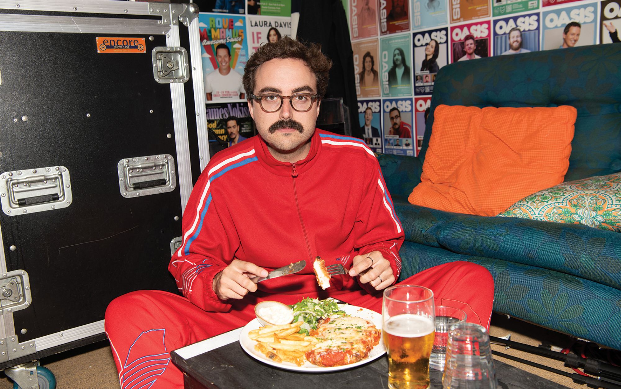 Daniel seated, wearing red tracksuit eating