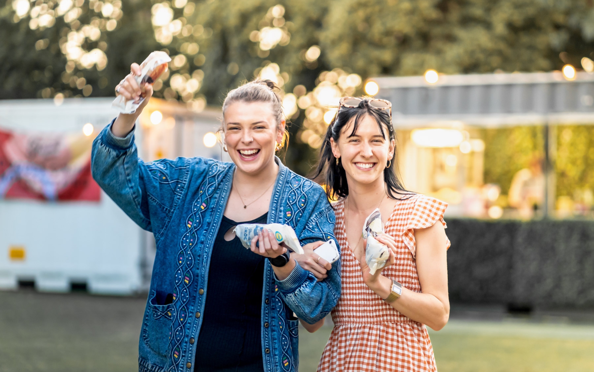 Two girls walking with snacks in their hands
