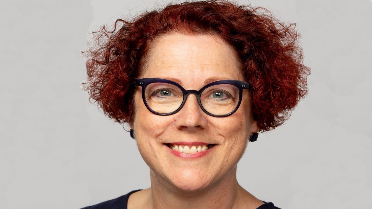 A headshot of Margot Riley, a woman with glasses and fuzzy red hair. 