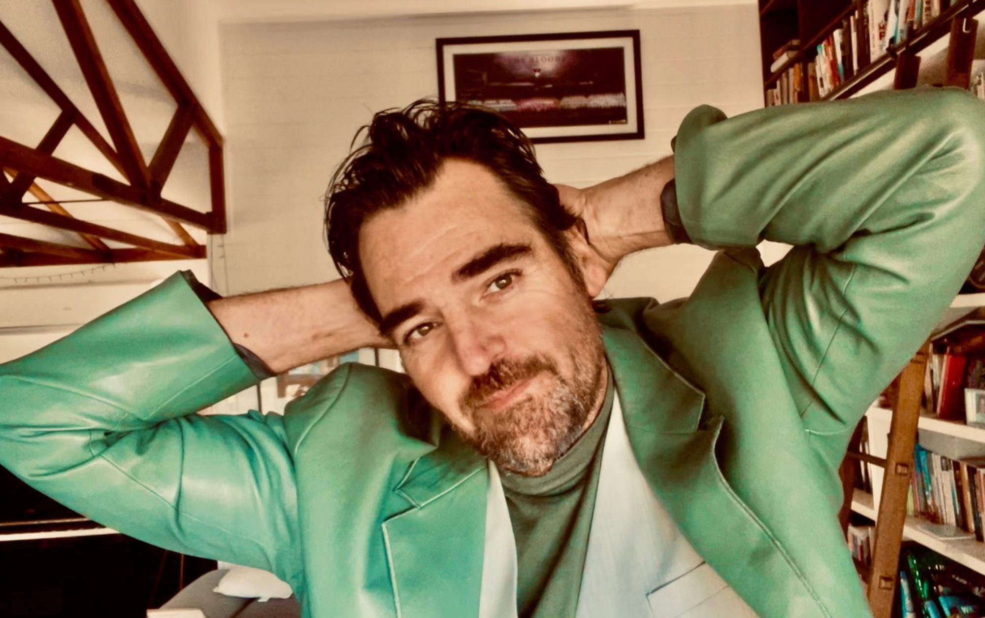 Man with beard smiling with hands behind his head