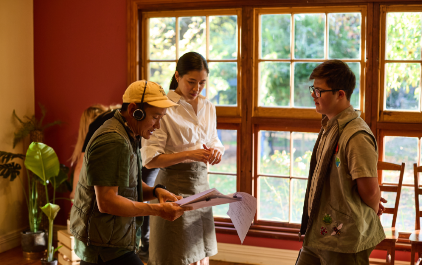 Sound technician talking to a student, and another female teacher standing to the side in a light filled room